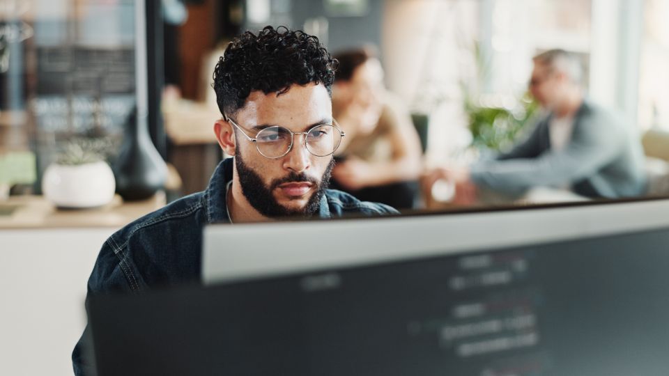 Bildinhalt: Mann sitzt am Computer in einem Büro